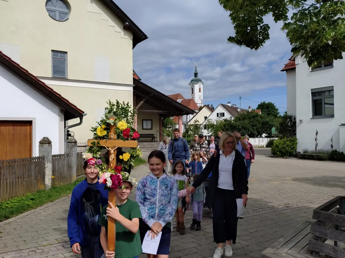 Die Kinder starten mit dem geschmückten Kreuz am Pfarrheim